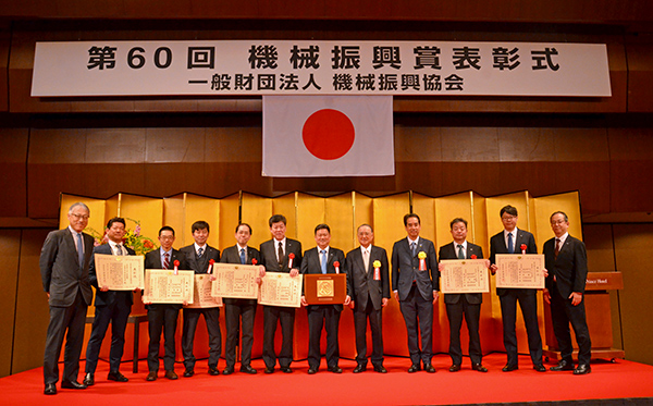 表彰式の様子（写真左から） IHI常務執行役員 資源・エネルギー・環境事業領域長 小澤、IHI原動機 取締役技術センター長 田村、 同社 増田主査、同社 眞島主査、IHI技術開発本部 技術基盤センター エネルギー変換技術部 廣瀬主幹、IHI原動機 倉井アシスタントマネージャ、同社 代表取締役社長 保坂、機械振興協会 釜会長、 経済産業省 製造産業局 伊吹局長、IHI原動機 技術センター アンモニアプロジェクト部長 戸田、 同社 佐々木、同社 舶用事業部長 水澤