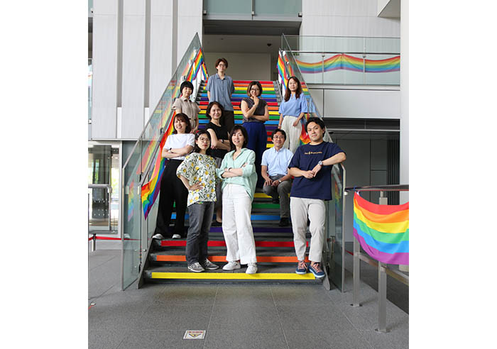 Members of the Pride Month secretariat pose in front of rainbow decorations at the Head Office building